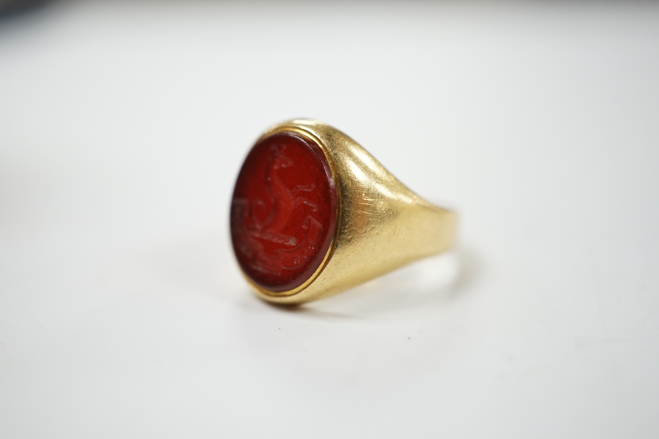 An 18ct and oval intaglio carnelian set signet ring, carved with family crest and motto, size K, gross weight 6.9 grams.